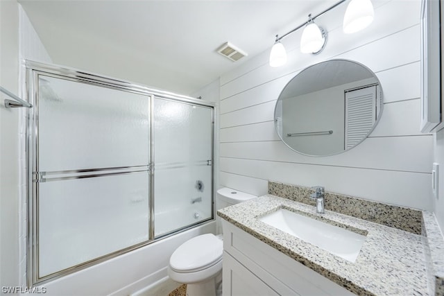 full bathroom with vanity, bath / shower combo with glass door, and toilet