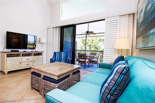 living room featuring ceiling fan, light tile floors, and a towering ceiling