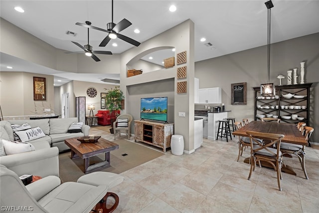 living room featuring a high ceiling, light tile patterned floors, and ceiling fan