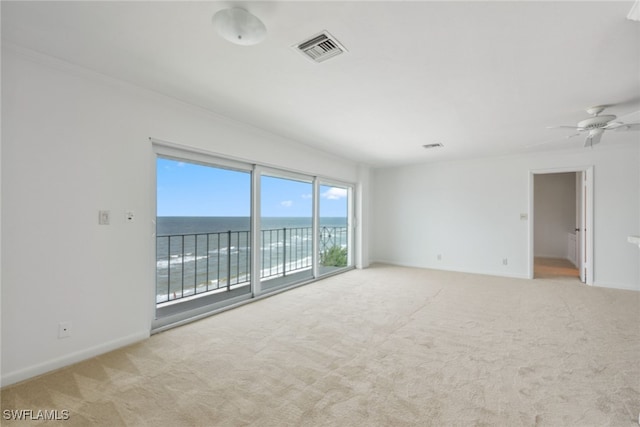 spare room featuring a water view, ceiling fan, and light carpet