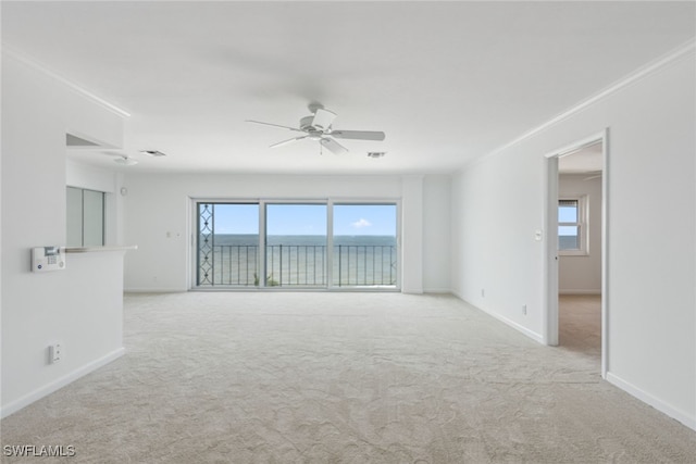 carpeted empty room featuring crown molding, a wealth of natural light, ceiling fan, and a water view