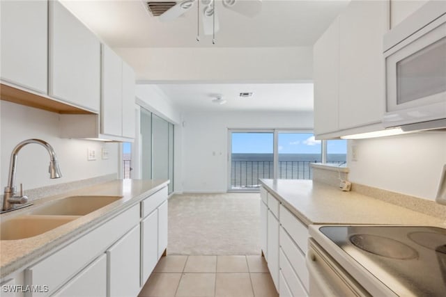 kitchen with a sink, electric range oven, white cabinetry, light countertops, and white microwave