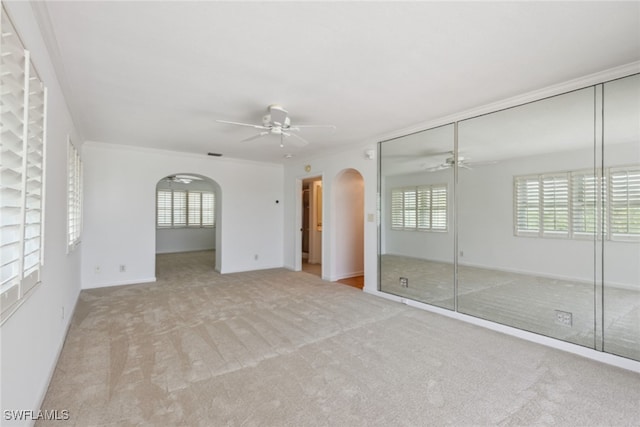 unfurnished bedroom with a closet, a ceiling fan, arched walkways, and carpet floors