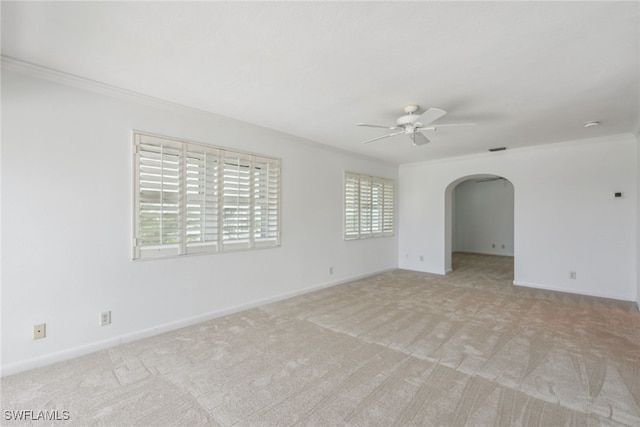 spare room with light colored carpet, a wealth of natural light, ornamental molding, and ceiling fan