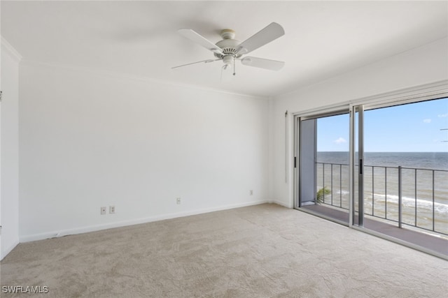 unfurnished room featuring crown molding, carpet flooring, ceiling fan, and a water view