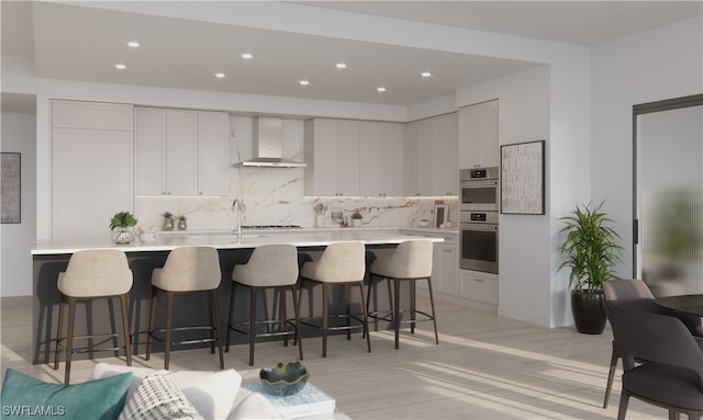 kitchen featuring backsplash, wall chimney exhaust hood, a breakfast bar area, and white cabinetry