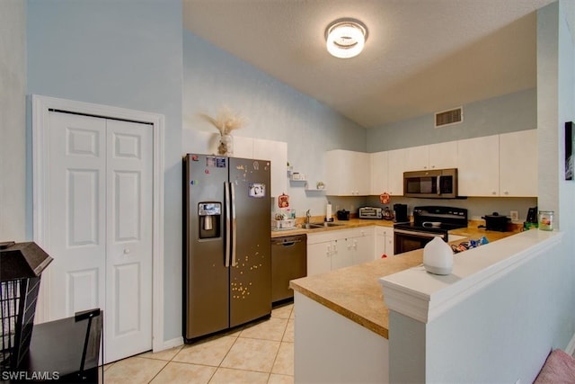 kitchen with stainless steel appliances, light tile floors, kitchen peninsula, white cabinets, and sink