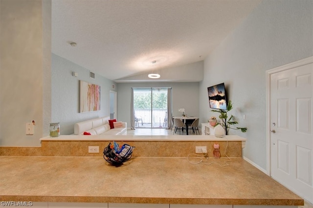 kitchen featuring kitchen peninsula, a textured ceiling, and lofted ceiling