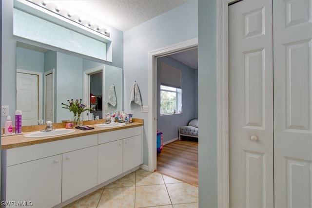 bathroom with a textured ceiling, wood-type flooring, and dual bowl vanity