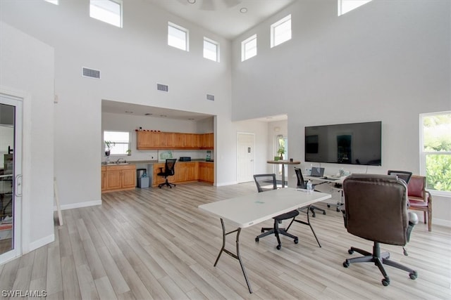 home office featuring a high ceiling and light hardwood / wood-style floors