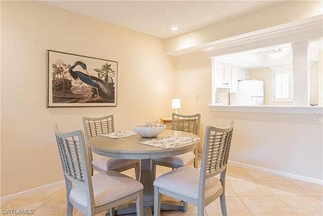 tiled dining room with ceiling fan and decorative columns