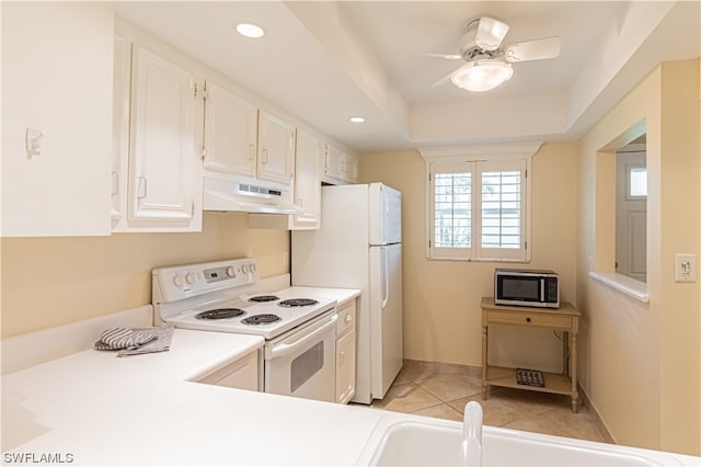 kitchen with light tile flooring, ceiling fan, white appliances, white cabinetry, and a tray ceiling