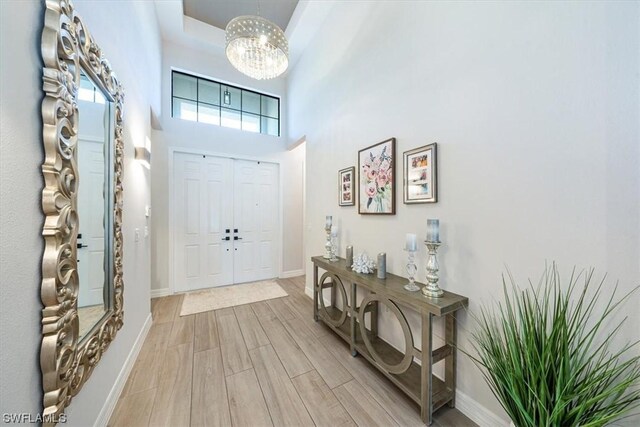 foyer with light hardwood / wood-style flooring, a towering ceiling, and a chandelier