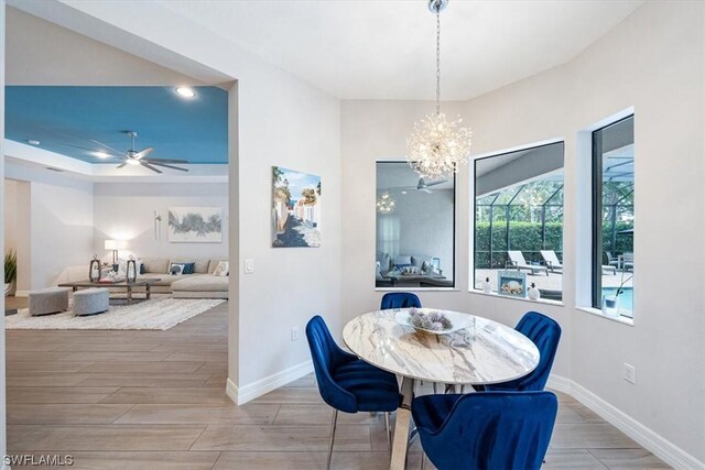 dining area with ceiling fan with notable chandelier and hardwood / wood-style flooring