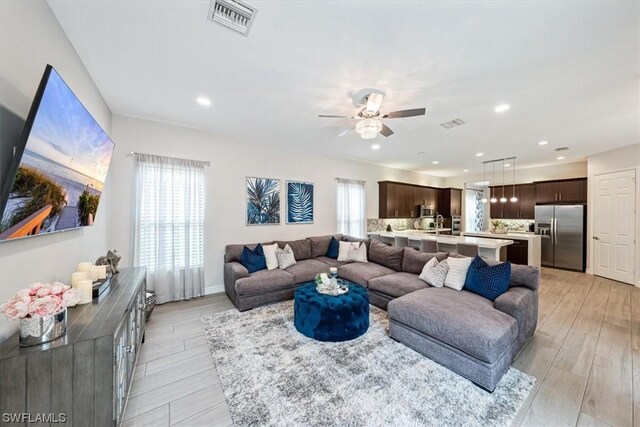 living room with ceiling fan and light hardwood / wood-style flooring