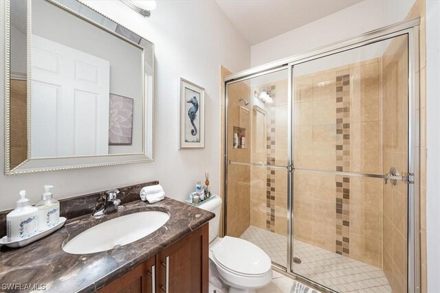 bathroom with vanity, toilet, and a shower with shower door