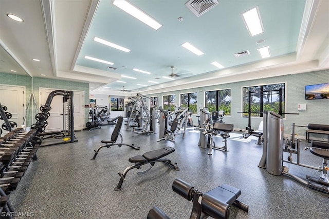 exercise room featuring ornamental molding, a raised ceiling, and ceiling fan