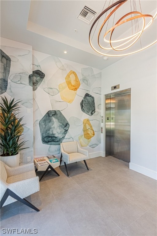 interior space with light tile floors, elevator, a tray ceiling, and an inviting chandelier