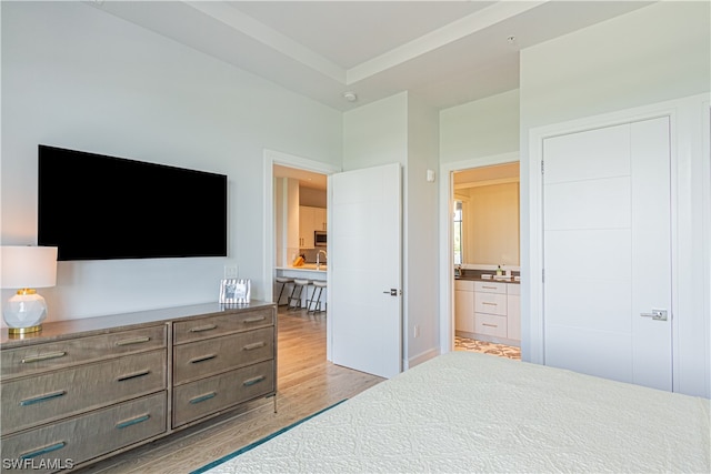 bedroom featuring connected bathroom and light hardwood / wood-style flooring