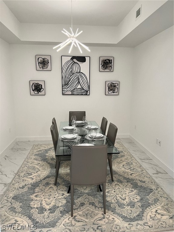 tiled dining space with a chandelier and a tray ceiling