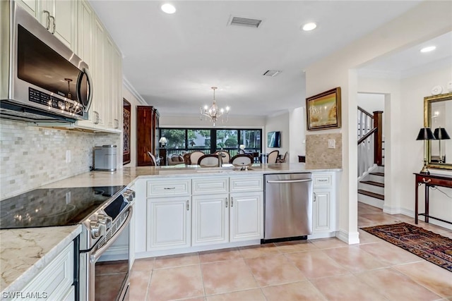 kitchen with decorative backsplash, an inviting chandelier, light tile patterned floors, and appliances with stainless steel finishes