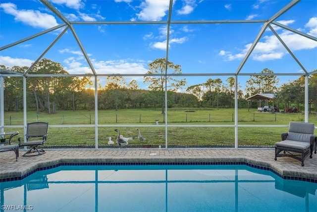 view of swimming pool featuring a lawn, a patio, and a lanai