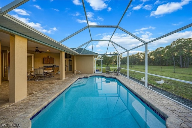 view of swimming pool featuring glass enclosure, a yard, ceiling fan, and a patio area