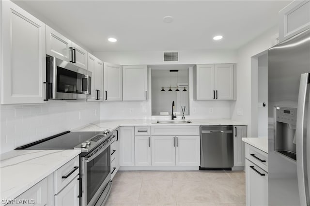 kitchen featuring tasteful backsplash, light tile patterned floors, light stone counters, stainless steel appliances, and sink