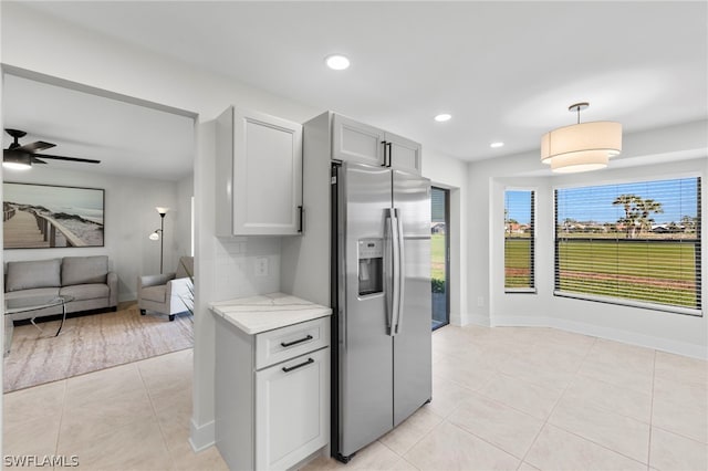 kitchen featuring light tile patterned floors, refrigerator, ceiling fan, light stone countertops, and decorative light fixtures