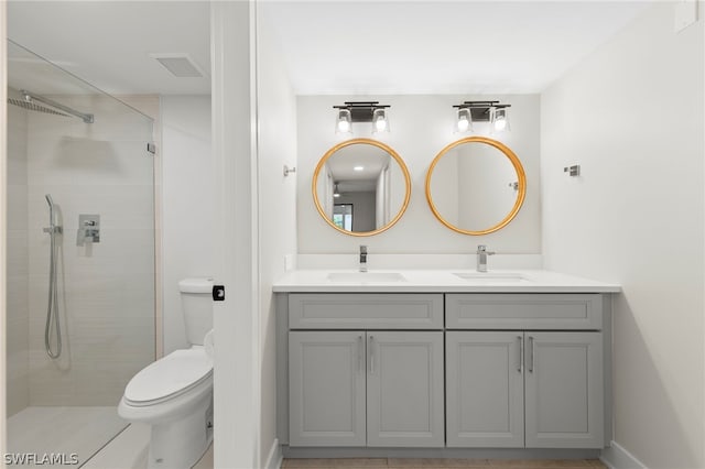 bathroom with tiled shower, double vanity, tile patterned floors, and toilet