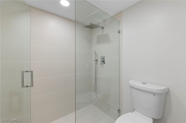 bathroom featuring a shower with shower door and toilet