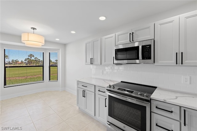 kitchen featuring stainless steel appliances, pendant lighting, decorative backsplash, light stone countertops, and light tile patterned floors