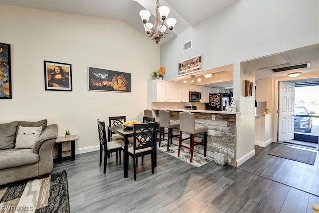 dining area featuring dark wood-type flooring, vaulted ceiling, and a chandelier