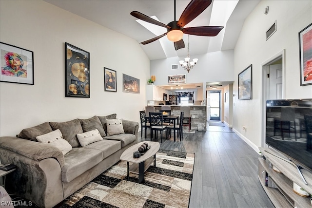 living room featuring vaulted ceiling, wood-type flooring, and ceiling fan with notable chandelier