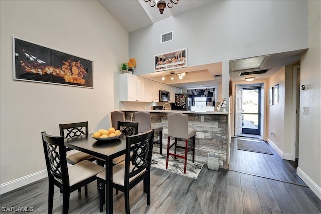 dining space featuring a high ceiling and dark hardwood / wood-style floors