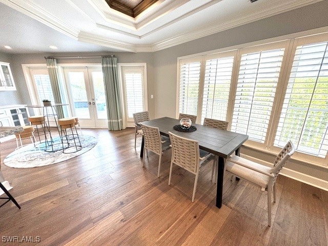 dining room featuring crown molding, french doors, wood-type flooring, and a healthy amount of sunlight