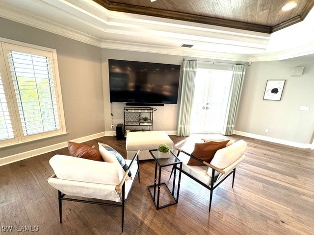 living room with wood-type flooring, crown molding, and a tray ceiling