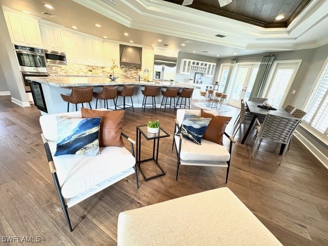 living room with crown molding, a raised ceiling, and dark hardwood / wood-style flooring