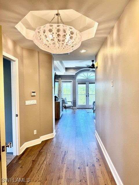 hallway with hardwood / wood-style flooring, french doors, and a tray ceiling