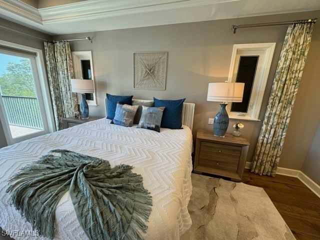 bedroom with hardwood / wood-style flooring, a raised ceiling, and ornamental molding