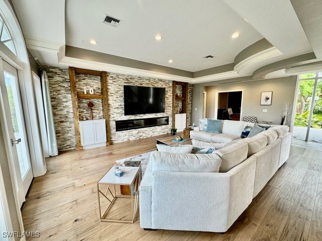 living room with light wood-type flooring and a raised ceiling