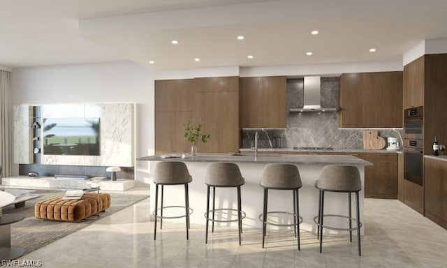 kitchen with wall chimney exhaust hood, tasteful backsplash, light tile flooring, and a kitchen breakfast bar