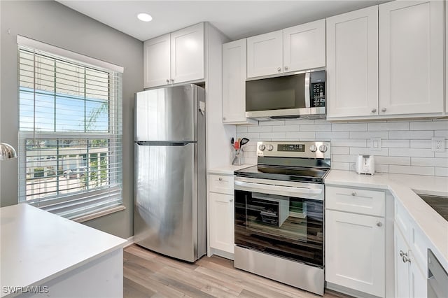 kitchen featuring backsplash, white cabinetry, light wood-type flooring, and appliances with stainless steel finishes