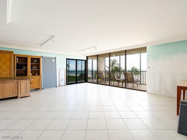 unfurnished living room with a wall of windows, track lighting, and light tile patterned floors