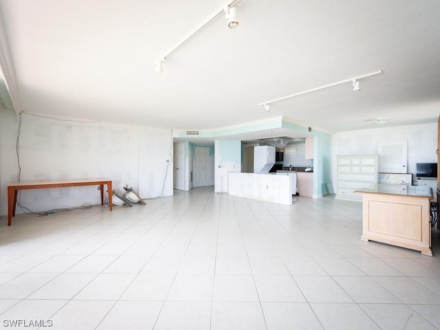 unfurnished living room featuring light tile patterned flooring and track lighting