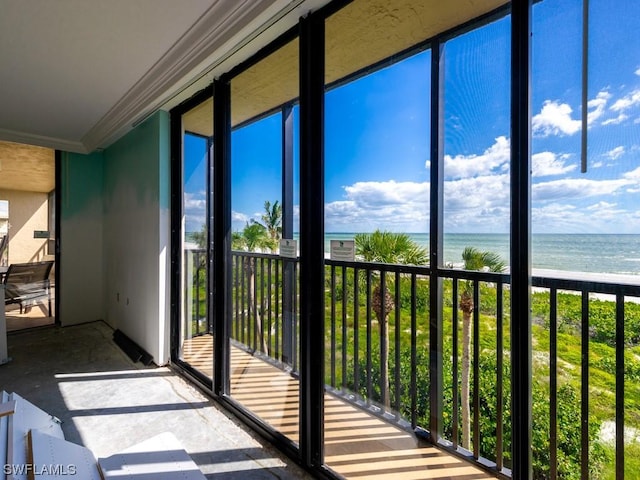 unfurnished sunroom featuring a water view and a view of the beach