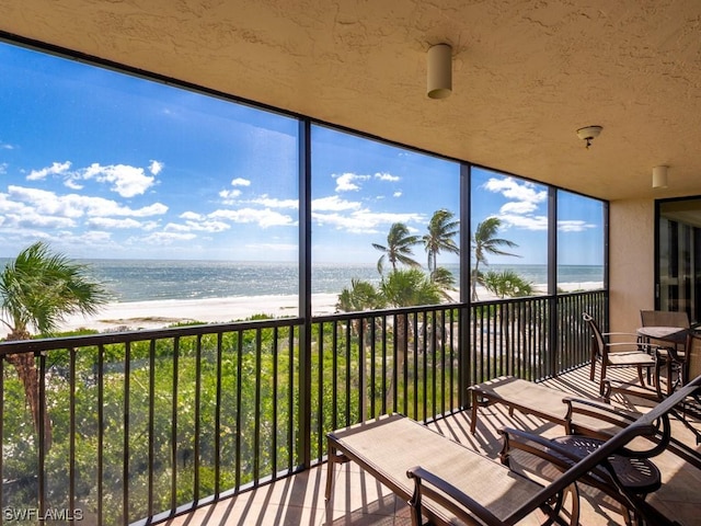 unfurnished sunroom with a water view and a beach view