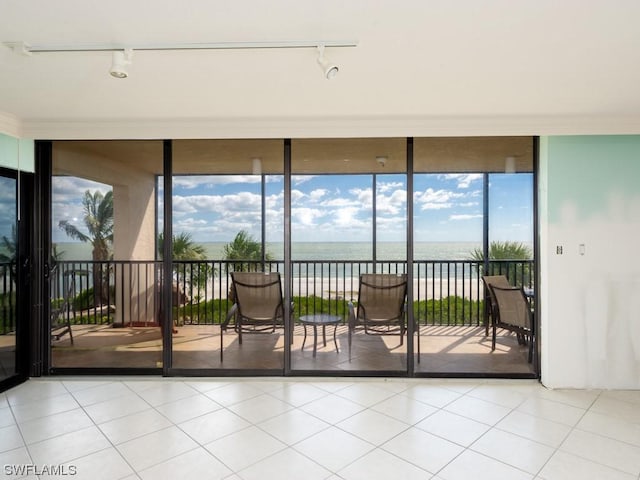 sunroom / solarium featuring a water view and track lighting