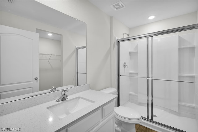 bathroom with toilet, a shower with door, vanity, and hardwood / wood-style floors