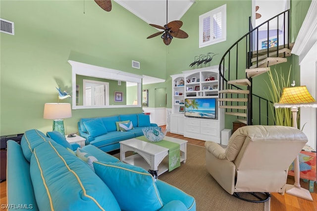 living room with hardwood / wood-style floors, ceiling fan, and a towering ceiling